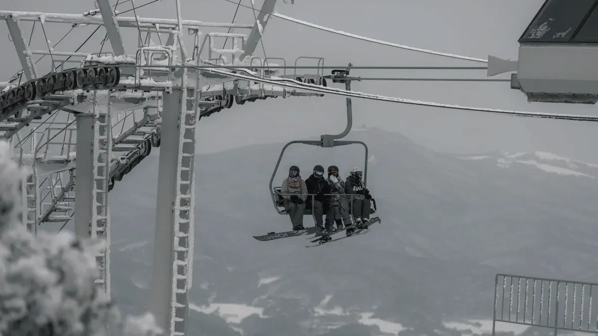 Skiers on a chairlift above a snowy valley