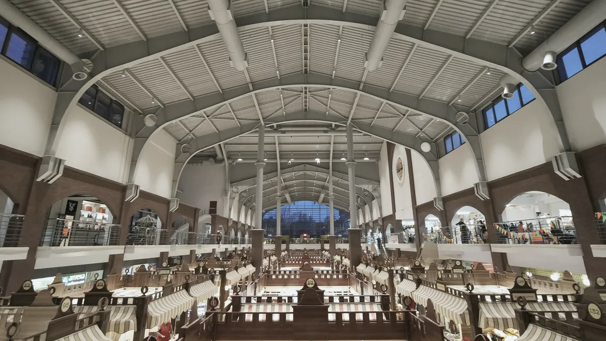 A covered market hall seen from the gallery, rows of stalls under a high steel roof