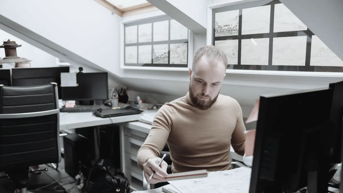 A design studio under a sloping roof, a designer at a desk between large screens