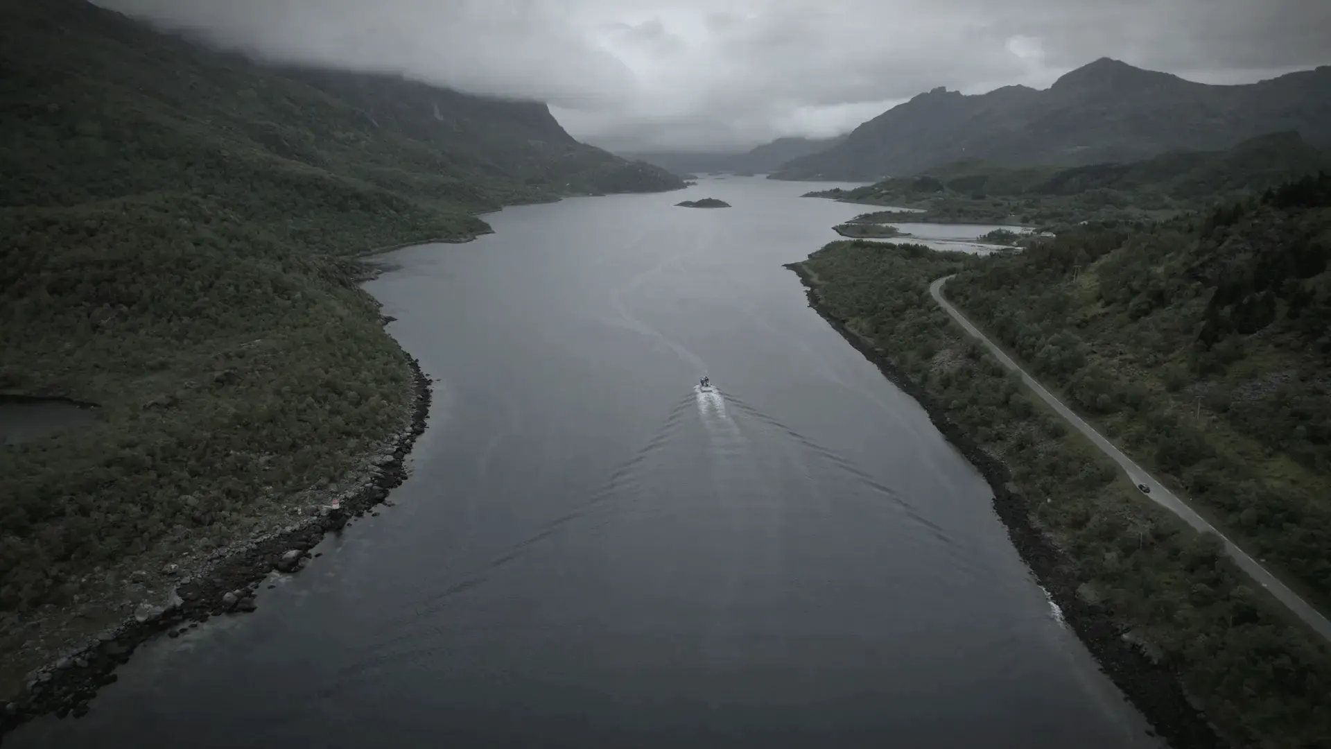 A small boat on a Norwegian fjord under low cloud, seen from the air